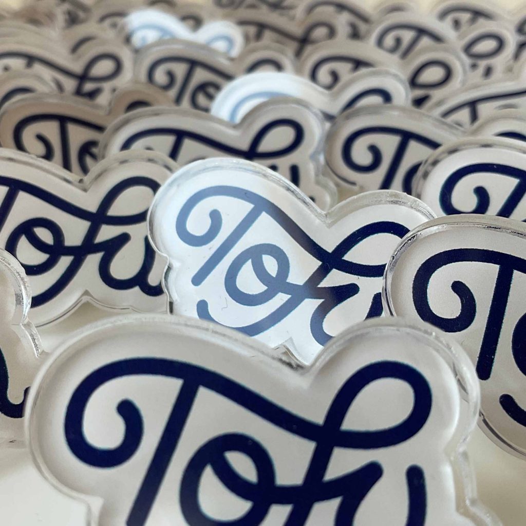 A crowded close-up of Tofu Type Foundry pins that use a smooth script font.